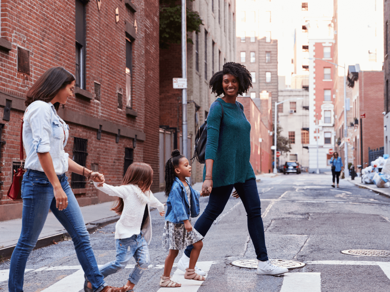 Two mother friends with daughters crossing road