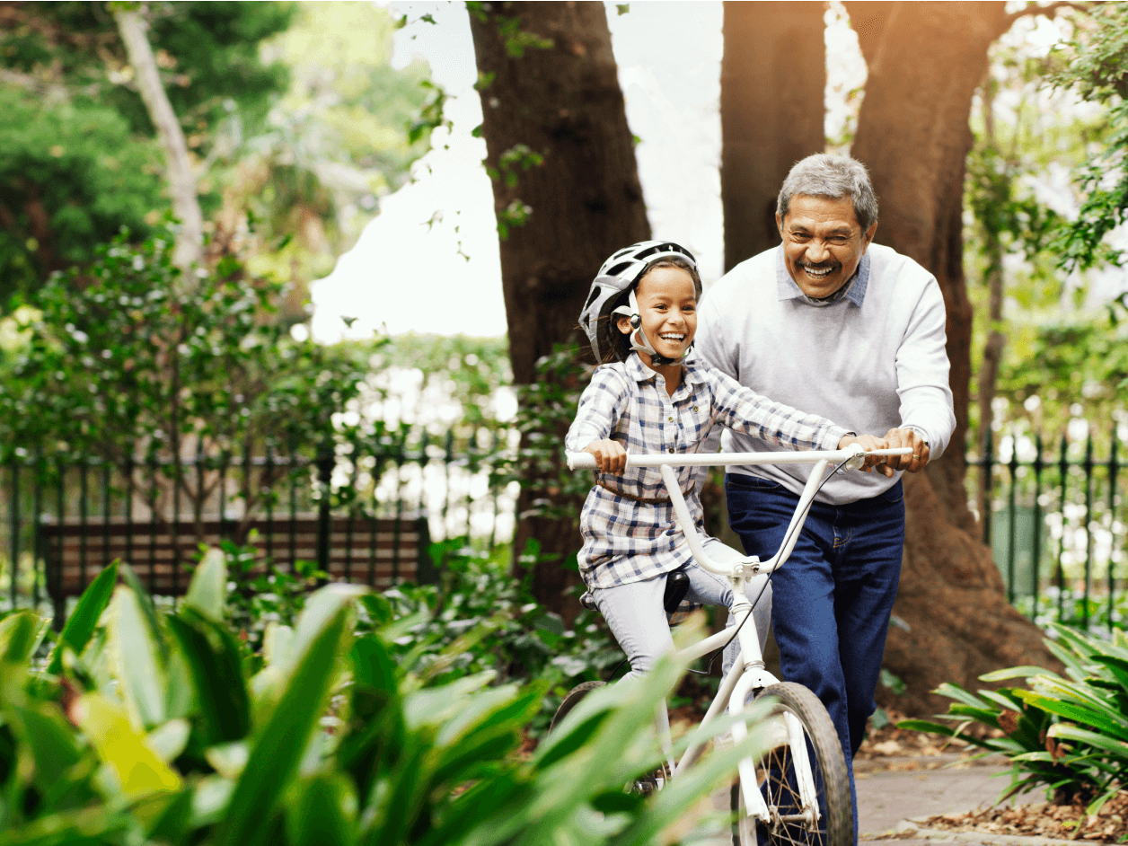 Shot of an adorable little girl being taught how to ride a bicycle by her grandfather at the park