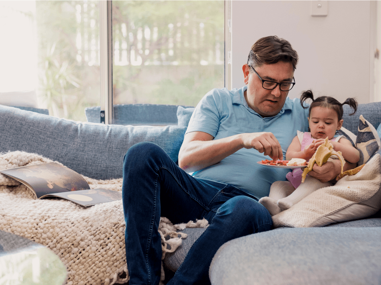 A grandfather feeds his granddaughter a healthy breakfast of fruit in his home in Perth, Western Australia